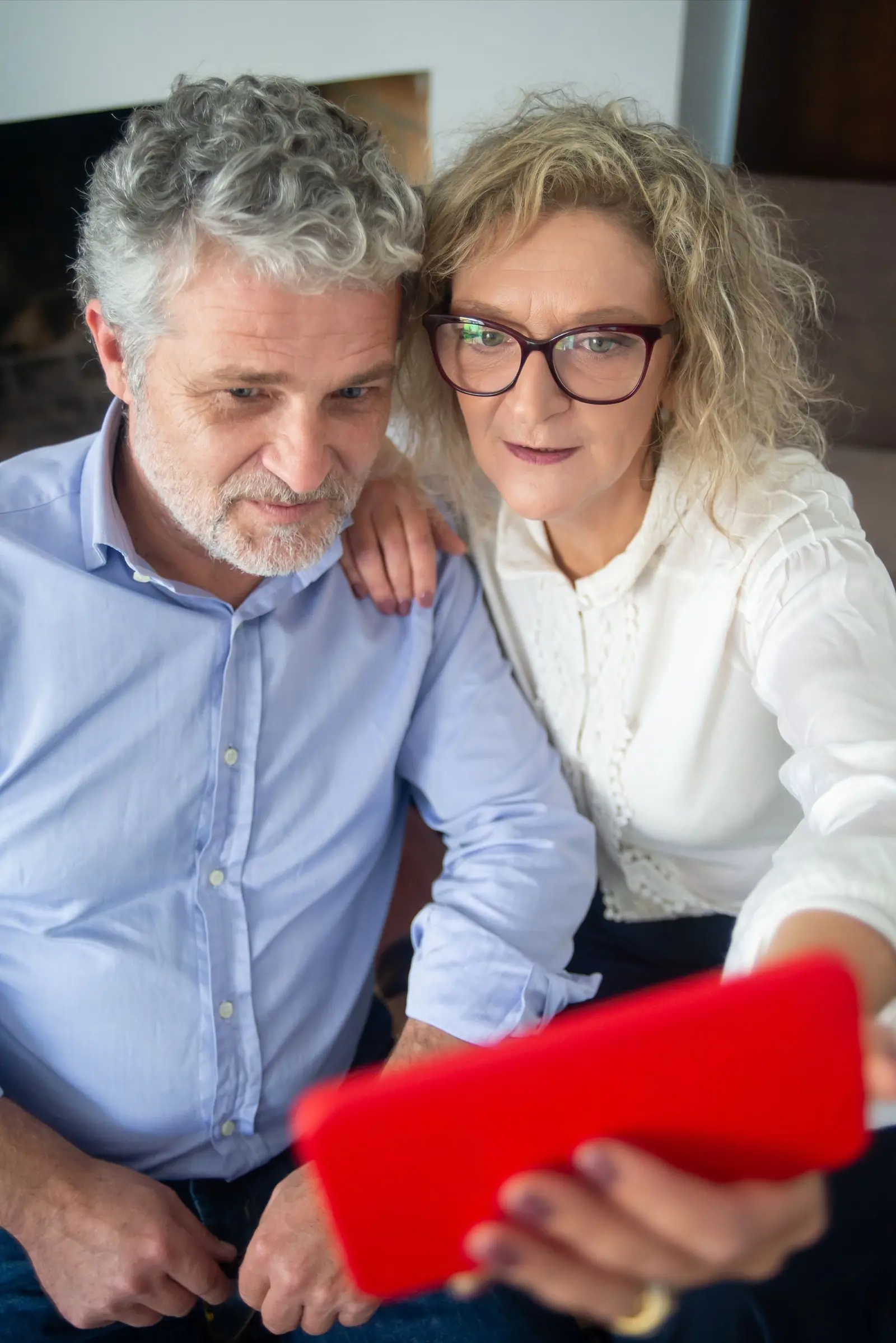 Two older adults looking at a phone together indoors