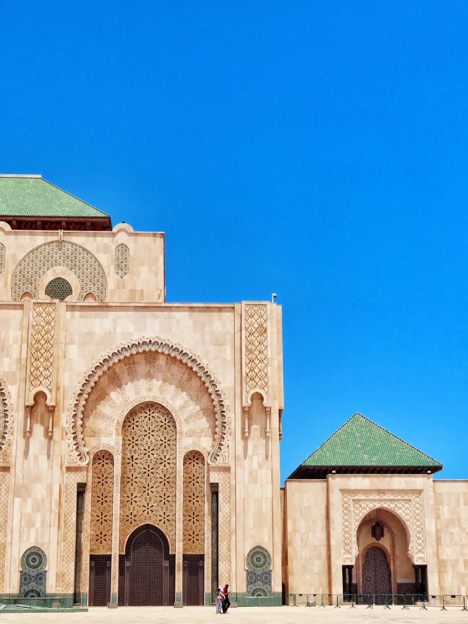 Carved stone entrance of the Hassan II Mosque under a clear sky