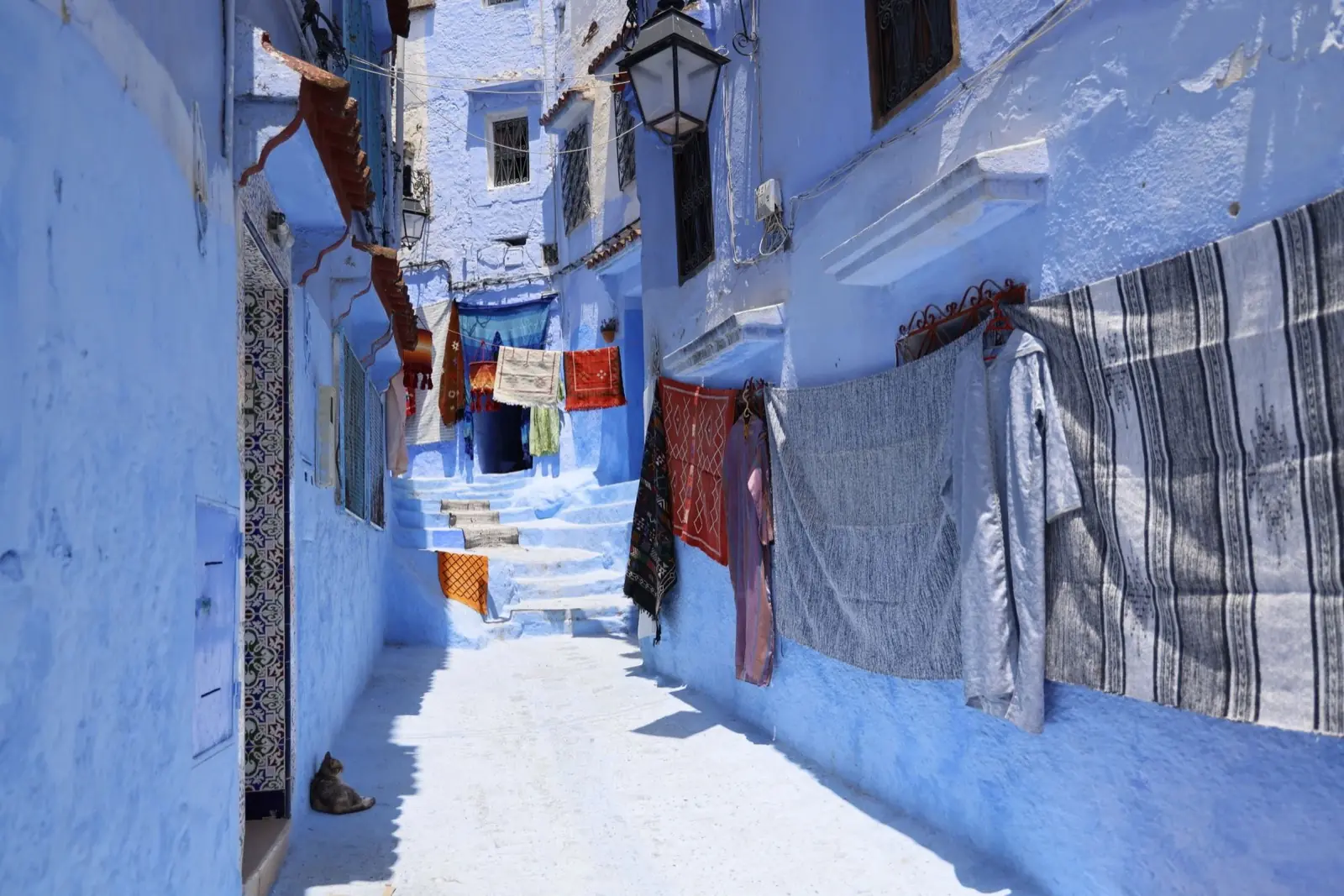 Clothes hanging across a blue alley between buildings