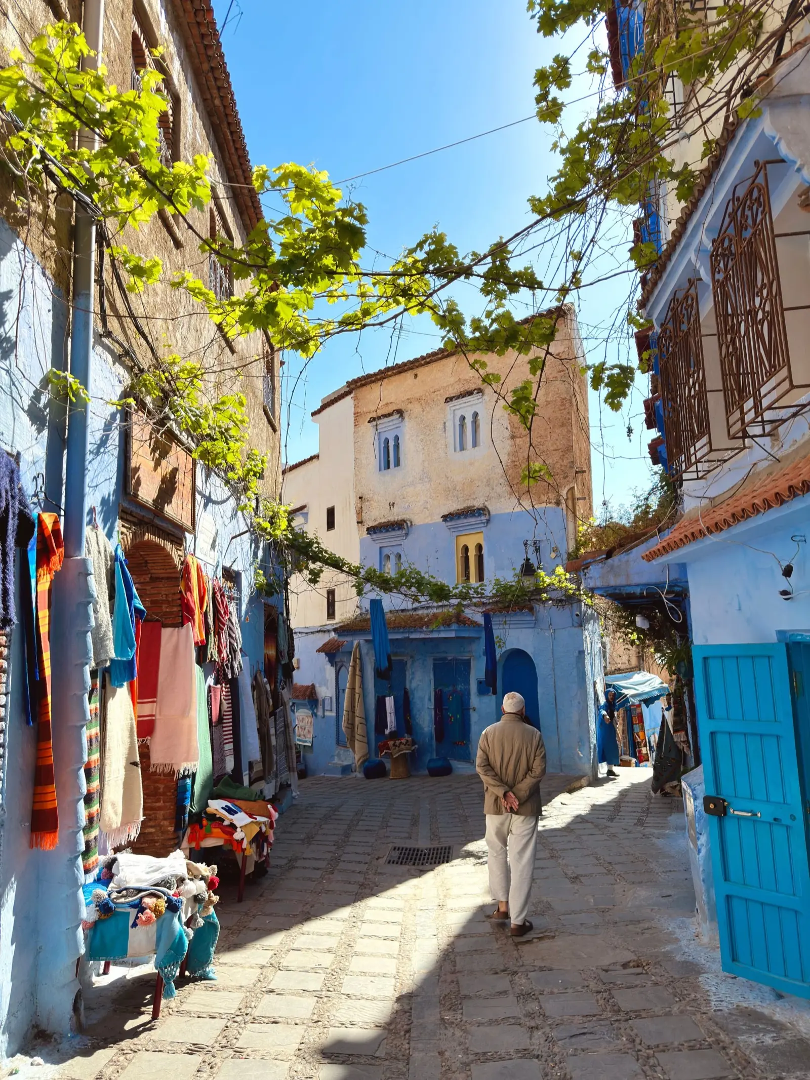 A blue street in Chefchaouen with a person walking away from the camera