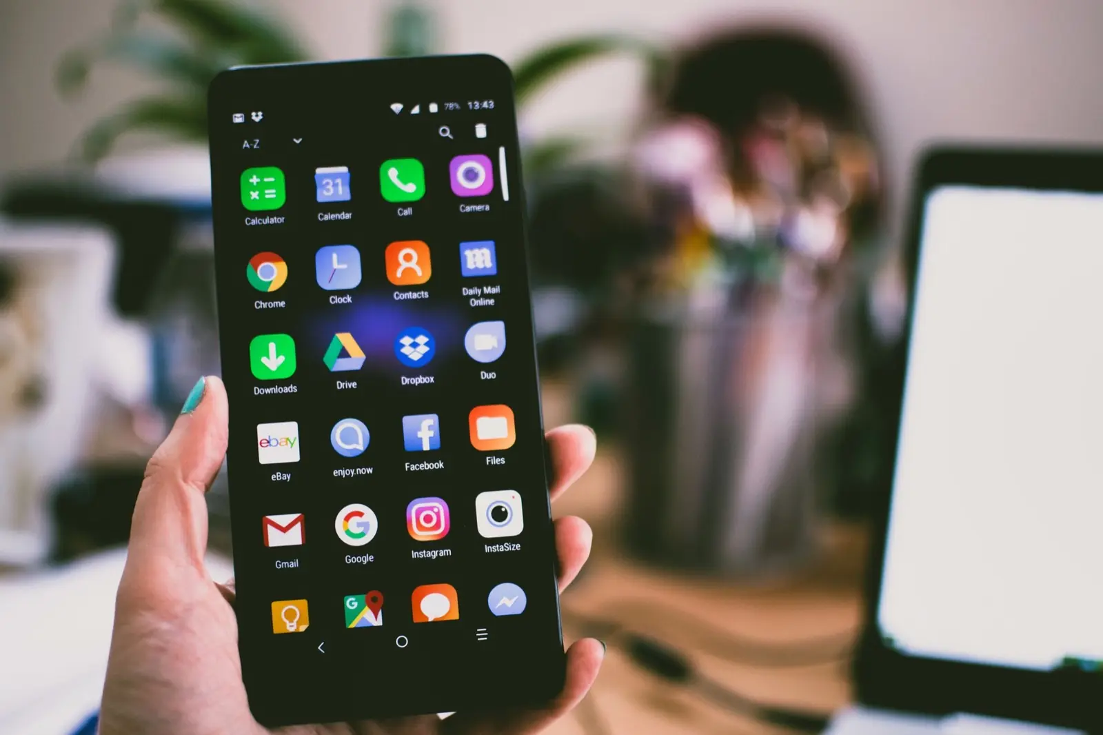 A hand holding a smartphone showing call, message, and map apps