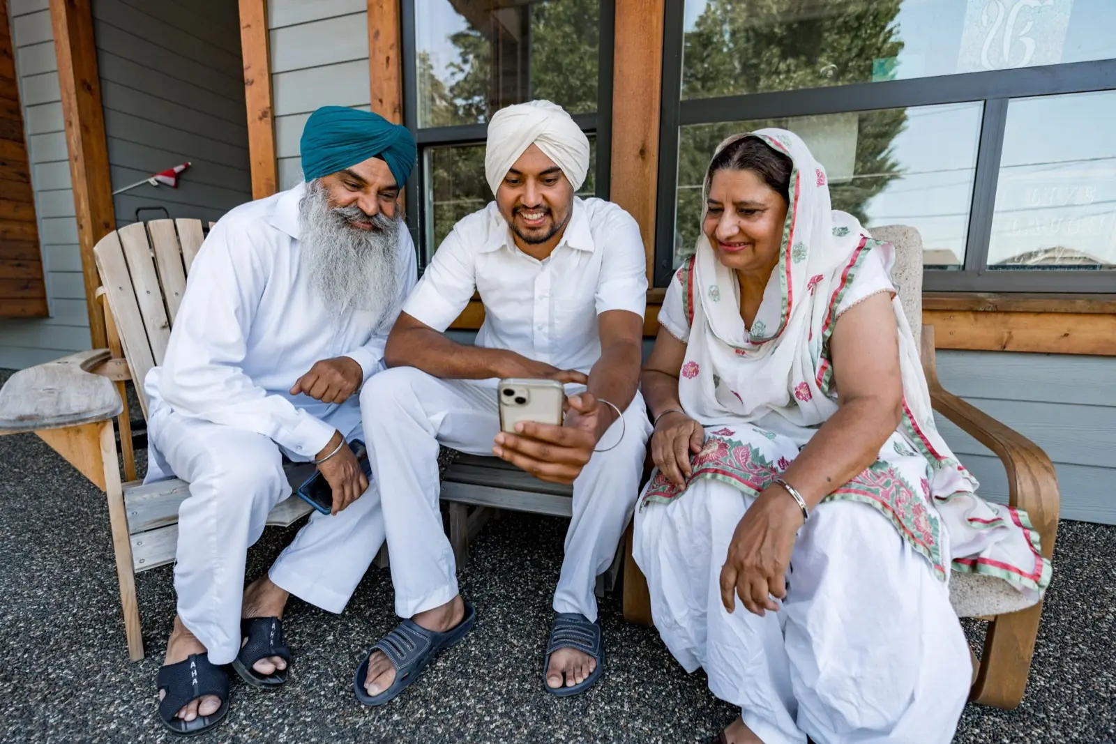 Three adults outdoors, sharing one phone