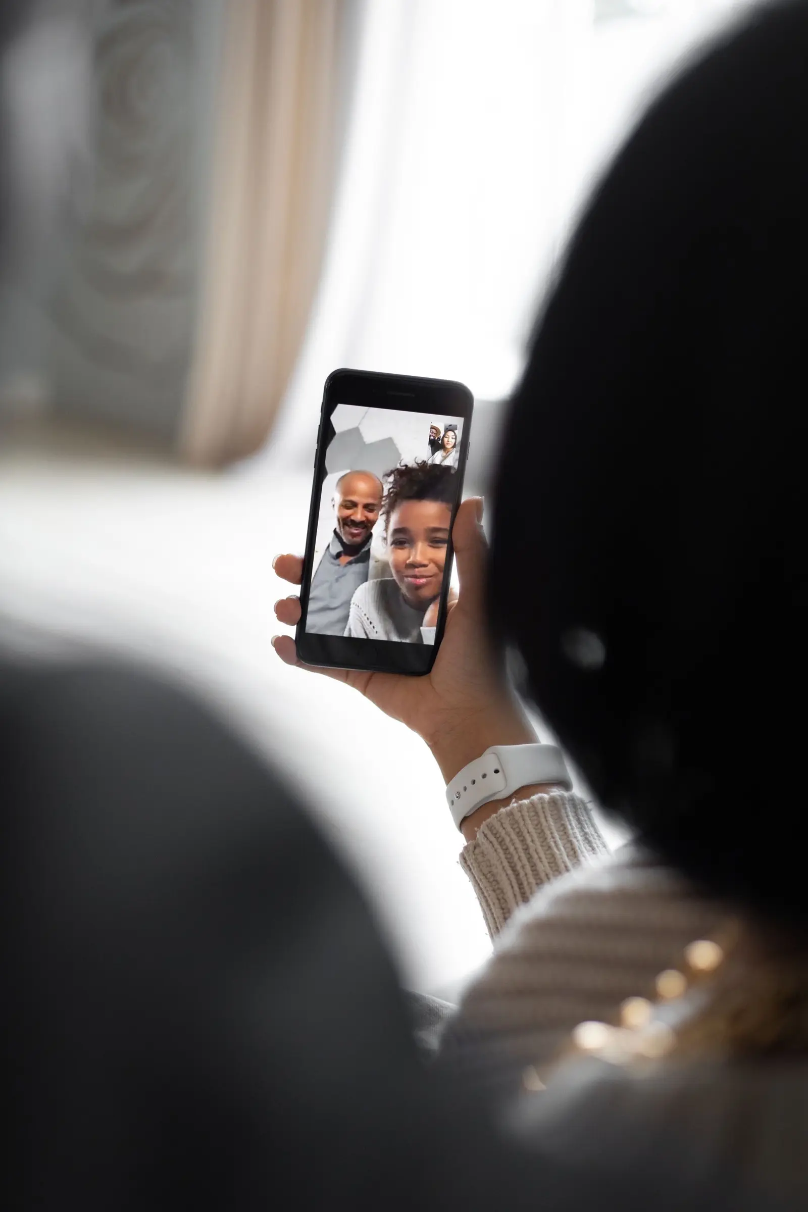A person on a sofa holding a phone during a video call